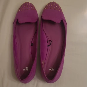 Lila ballerinaskor  - Lila ballerinaskor med gulddetaljer i stl 40. Har använts 3-4 gånger men tyvärr för små för mig. 