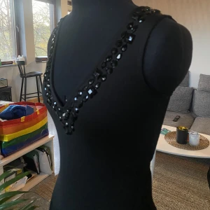 Stone front dress från Nelly - Figurnära miniklänning från Nelly med v-ringning, bling och mesh rygg samt cool skärning på sidan. Klänningen är oanvänd, taggen är fortfarande kvar. Står storlek S men passar XS.