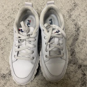 Vita Fila skor (kvinna/tjej) - Ett par vita Fila skor i storlek 38.  Priset kan ändras. Ta kontakt för snabb affär. 