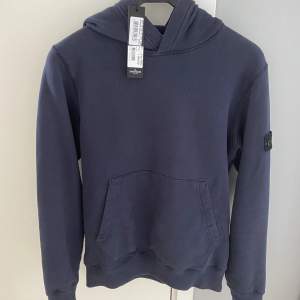 Mörkblå stone island hoodie i nyskick! Kommer med kvitto och tag.  Köpt på NK i Göteborg.  Storlek: 14/164 passar bra upp till 174  Nypris, 2299, mitt pris 750