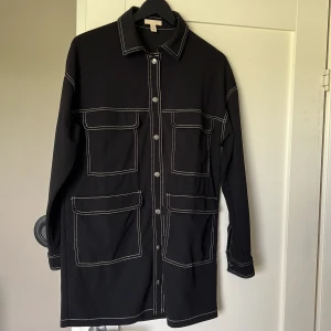 Klänning/skjorta/tunn jacka  - Från H&M svart med vita sömmar. Storlek XS men är oversized så passar även S och M.  