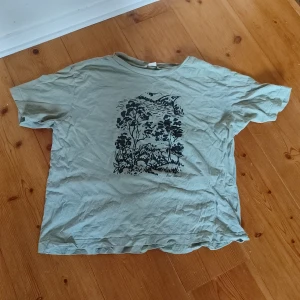 Grön t-shirt med skogstryck - Jättemysig t-shirt med vackert tryck på med inga skador och har används sällan! 