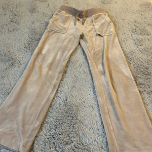Juicy byxor beige!  - Säljer dessa juicy byxor! Har två små hål vid vänstra knät! Fickan har gått sönder lite och en av de silvriga på snöret har jag tappat bort. Därför säljs de för lite. Köptes för 1100kr! Står ej av postens slarv! Används mycket men inte längre!💗