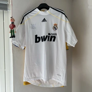 Real Madrid 2009-2010 hemmatröja - Säljer en real Madrid tröja storlek M, fint skick inga skador mer än att climacool logan därnere har lossnat. ‼️Vet ej om den är äkta eller inte.‼️ Den är också lite smutsig. 350kr eller bud