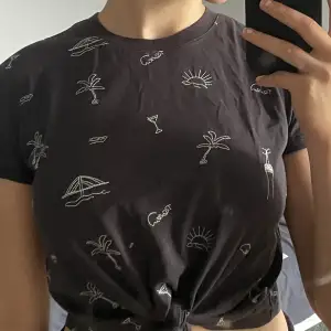 T- shirt med knyte i midjan med broderade mönster 