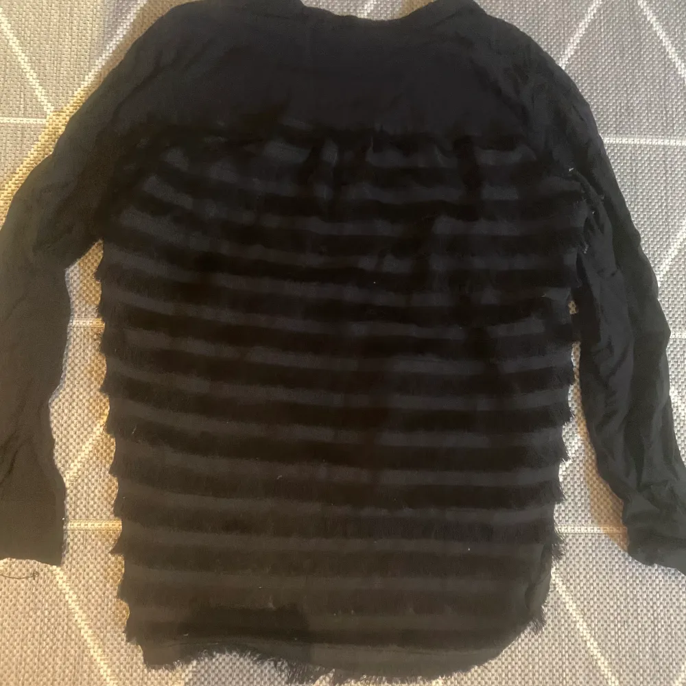 en svart blus med fjäder detaljer på baksidan. jättefin . Puserot.