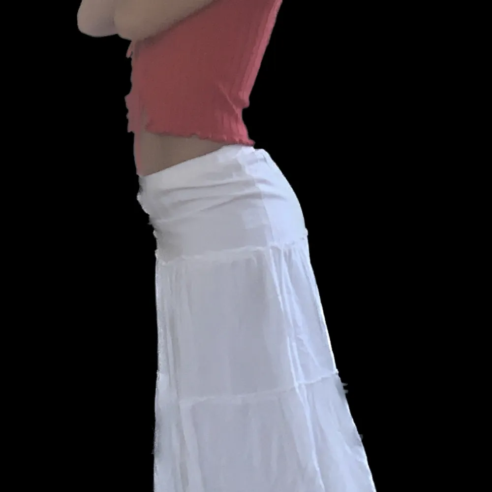 Flödig maxikjol i vitt med stretchig midja och volangdetaljer. 85cm längd, 61cm midja (stretchig)    *första bilden är lånad*. Kjolar.
