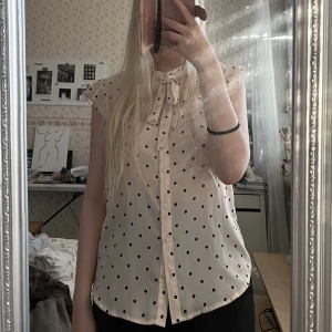 Rosa blus med prickar - Supersöt ljusrosa blus med svarta prickar samt knappar, volang vid ärmarna och snörning vid halsen!💓 Från Mint & Berry i strl 34!🫶🏻