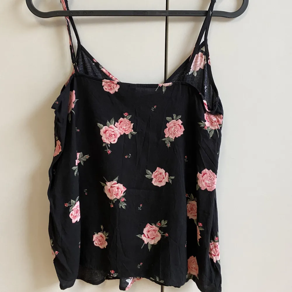 Ett svart linne med rosa blommor som tryck. Använd ett fåtal gånger men är som i nyskick!. Toppar.
