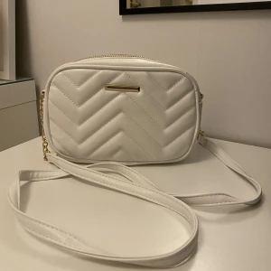 Handväska  - En jättefin handväska med guld detaljer i nyskick, aldrig använd! Kom med prisförslag! Tillkommer bara ett långt band!