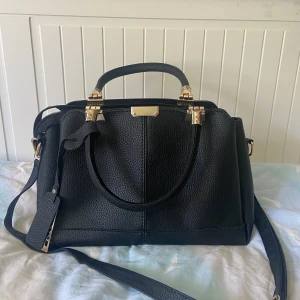 Svart axelremsväska med gulddetaljer - Jättejättefin mellanstor väska! Såå rymlig med jätte många fack! Aldrig använd!