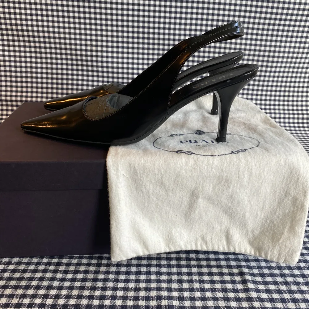 Svarta läder slingback klackskor ifrån Prada (7 cm klack). Skorna är i gott skick. Orginal skopåse och kartong medföljer.. Skor.