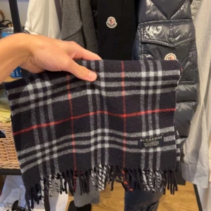 Burberry Halsduk - Burberry Halsduk i utmärkt skick, 100% lammull. Nypris 4600 mitt pris 900kr. Inga märken, fläckar etc. Bara att skriva vid frågor eller funderingar! :)