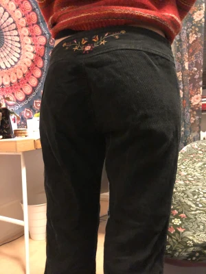 Manchesterbyxor bootcut - Ett par svarta manchesterbyxor med supergulliga broderi. Personen på bilden är 170 och brukar ha waist 27. 