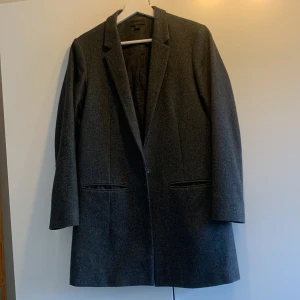 Grå kappa - Mörkgrå ullkappa. Bra skick men saknar knapp så går inte att stänga fram Tyvärr förliten för mig som har storlek small, tror den skulle passa på nån som har xs Längd - 82 Ärmlängd - 73 (från axeln)