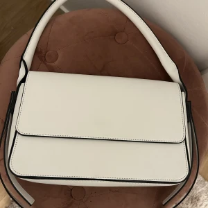 Vit handväska  - Vit handväska med detaljer på sidorna. 