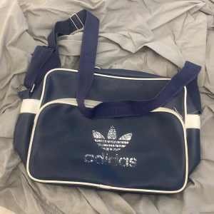 Addidas väska - Fin mörkblå addidas väska. Väskan är i bra skick men trycket är slitet. Men det är inte så att det flagnar av eller så. 