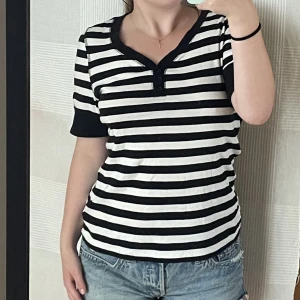Randig tshirt - Svartvit randig V-ringad tshirt med jättegulliga knappar och fin passform! Jag har vanligtvis S/M och storleken passar bra