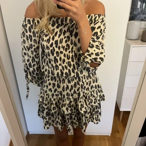 Leopardklänning - Gullig offshoulderklänning i leopardmönster, går jättebra att ha som kjol med stickad tröja över. I världens skönaste material och aldrig använd med lappen kvar 