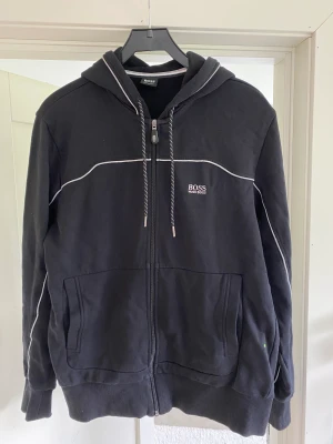 Hugo Boss zip hoodie - Säljer min Hugo Boss hoodie då den blivit för liten och används därför inte längre! Kan mötas upp eller skicka på post.  Skick 9/10 Storlek M