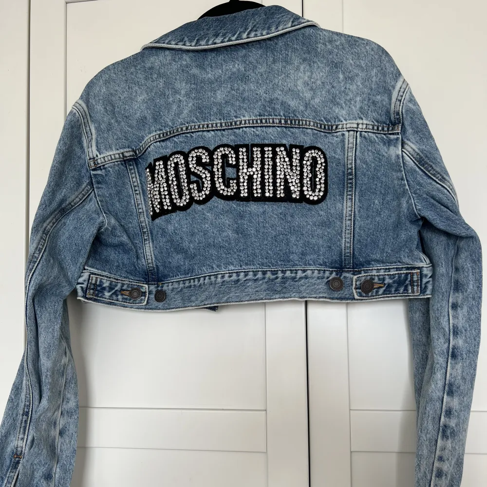 En äkta Moschino denim jacka som är cropped och utsmyckad på baksidan. Jättefin färg och passar till mycket. Använd endast 1 gång en kort stund, så den är så gott som ny i perfekt skick. Sista bilden är lånad. . Jackor.