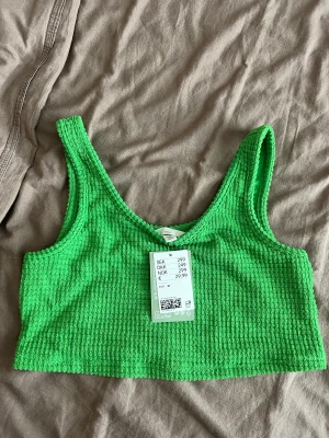 Crop top - Grön crop top från H&M med prislapp kvar i storlek M 