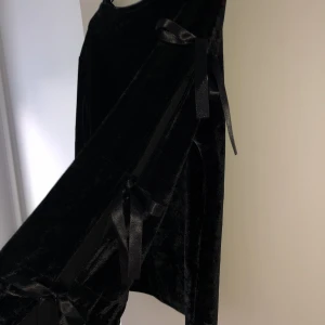 Svart tröja med slits på armarna - Svart sammetströja med öppna ärmar och knytdetaljer. 