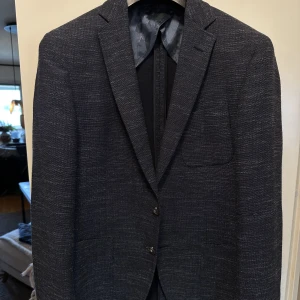 Hugo Boss / blazer - En snygg blazer från Hugo Boss! Färgen är i en snygg blå med lite struktur i sig! En enkel blazer att bära, går bra med det mesta. Jeans och T-shirt eller stickad tröja t.ex.  skicket är väldigt bra! Storlek: 48 , får en väldigt bra och fin passform!