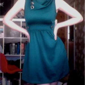 Blågrön klänning - Blågrön klänning i retrostil med knappdetaljer vid kragen och midjan. Jättebra skick, använd 1 gång. Storlek 36.