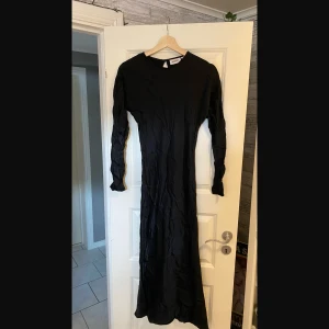 Svart Glansig Långklänning - Svart fin långklänning från WEEKDAY i storlek 34 (motsvarar XS). På sista bilden står ”Stryks i fuktigt tillstånd, 100% viskos”.  På bilderna är klänningen ostruken men kan stryka den innan leverans om det önskas!  
