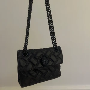 Kurt Geiger väska  - Kurt Geiger väska i en så cool mörk lila färg. Har lite slitage men fortfarande bra skick. Köpt i Paris för nypris ca 1600 kr. Dustbag finns!
