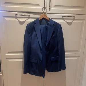 Marinblå Kostym från Dressman i storlek S - Kavaj storlek: 44 (slim fit) Byxor storlek: 30/30 (slimfit  Följer också med: fluga och näsduk i samma färg  Originalpris: 2,400kr *Använd en gång* *Priset kan diskuteras* 