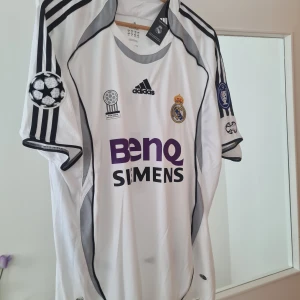 Real Madrid 2006-07 Hemmatröja - Real Madrid tröja från säsongen 2006-07 i storlek XL. Den har varit inramad och är helt oanvända, köpt i Spanien 2006 är helt äkta. Kan skickas vid behov MVH
