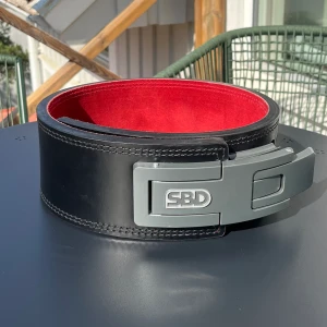 SBD bälte 13mm (M) - Kraftig konstruktion av specialbehandlat läder och har en helt ny typ av spänne. Godkänt för tävling. Storlek: M. Tjocklek på lädret: 13mm. Skick: 9/10. Nypris: 3000kr.