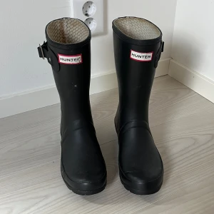 Hunter gummistövlar  - I den lite kortare modellen, nypris 1800 kr.  Passar 37,5-38 eller ner till 37 om man vill ha tjockare strumpor i. Använt skick därav priset se bilder. Fint skick utvändigt bortsett från skavet på loggan. 