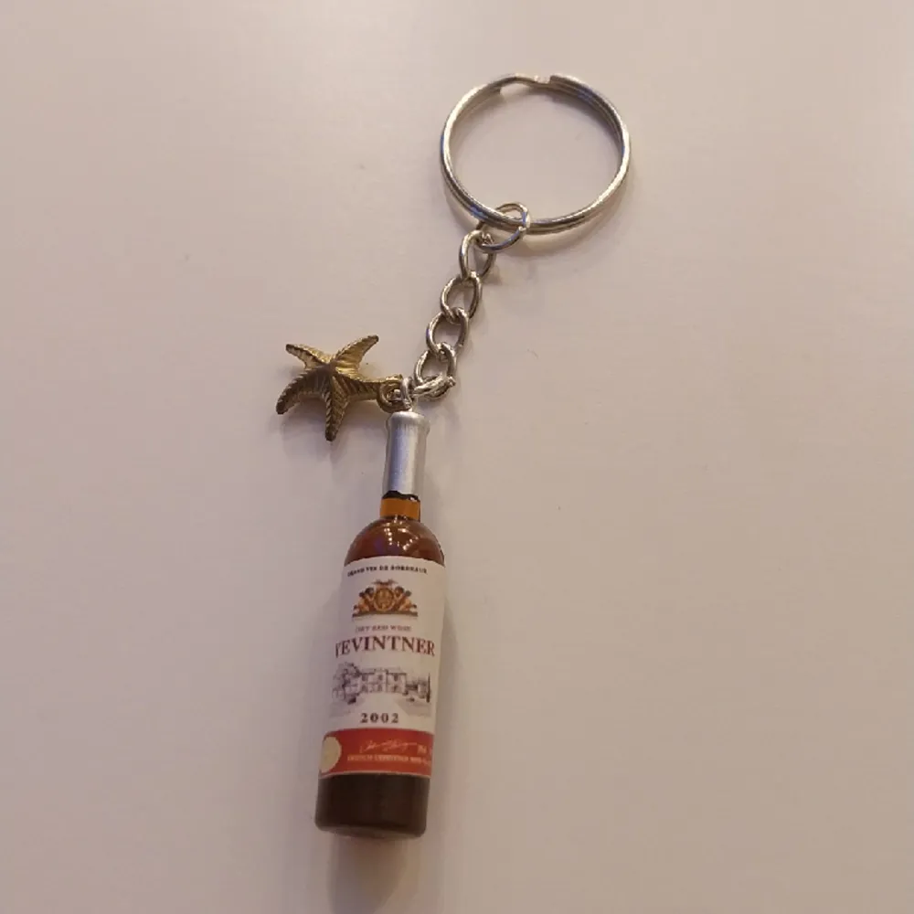 Handgjord nyckelring med 2 berlocker. En vin flaska och en liten sjö stjärna. . Accessoarer.