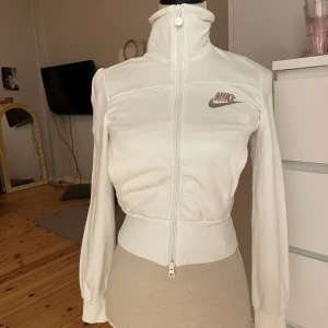 Nike träningströja - Superfin träningskofta ifrån nike. Sitter tajt i midjan, passar en xs. Croppad men slutar vid början av höften så perfekt för low Rise byxor till. Ingen luva. 