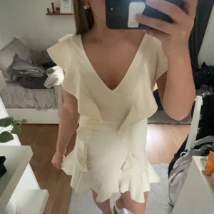 Gräddvit klänning - Säljer denna super fina klänning från hm, öppen rygg med fina volang detaljer. Perfek till student eller skol avslutning💕i storlek 40 men skulle säg att den passar mer som en 38