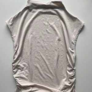 Topp - Topp med hög hals och rynkade sidor, lite kortare i modellen 