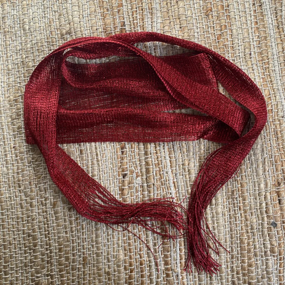 En smal halsduk i röd färg . Övrigt.