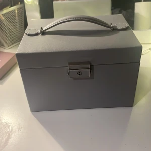 Smyckeskrin  - Grått smyckeskrin i fint sick. Säljs pågrund av ingen användning. Det kommer med en liten nyckel så att men kan låsa det och det är från Ur och Penn. Köptes för ca 300 säljs för 200