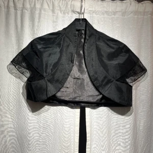 Svart bolero - Svart bolero i satintyg med paljetter vid axlarna. Finns ingen lapp men uppskattar storlek xs/s💓