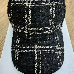 Svart Tweed Guess keps.  Den har några små svarta paljetter broderade, mycket detaljerade.  Endast använd en eller två gånger.