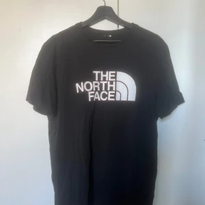 The North Face t-shirt - En svart t-shirt med röda detaljer på loggan. Det stora trycket är framsidan😊 Har visst klippt bort lappen med storleken på men skulle uppskatta den till en M!