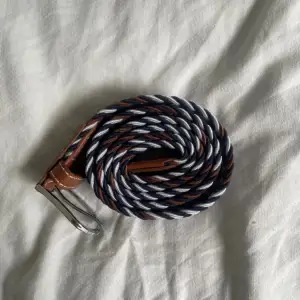 Oanvänd stretchig flätat bälte i färgerna brun, vit och mörkblå