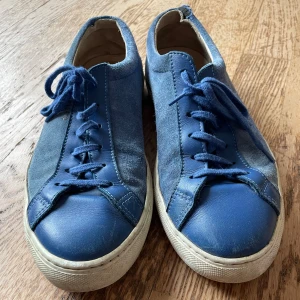 Axel Arigato blå skor - Blå sneakers från Axel Arigato! Mycket fina skor men med lite slitage vid ena skon vid hälen som syns på bilden! Strl står ej i skon men jag har 43-44 och dessa passar fint!