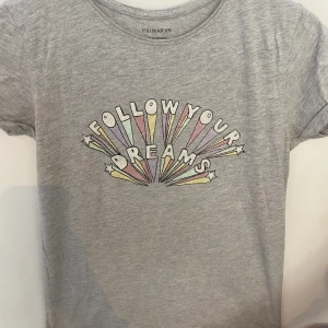 Grå t-shirt  - Grå tröja med en mening i mitten med lite ljusa pastellfärger med glitter på