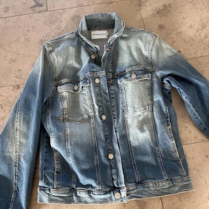 Calvin Klein jeansjacka och Peak Performance  jacka - Snygg, välvårdad jeansjacka från Calvin Klein. Stl. 16 år men passar även XS-S.  Vit, fin och välvårdad Peak Performance windbreaker m ljusblå detaljer och luva. Stl. XS.  Finns i Halmstad (Kan levereras vid området) Först till kvarn 