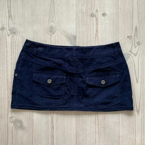 Lågmidjad mörkblå kjol - Mörkblå lågmidjad kort kjol från Marie Lund som jag har sytt upp från en längre kjol. Fint skick. Storlek 38 men passar mig som brukar ha 36. Den är 29 cm lång och 40 cm tvärs över midjan. Använd gärna köp nu!