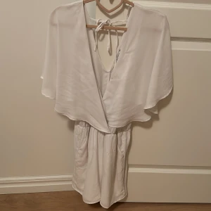 Gina tricot sommar klänning - Vit byxdress från ginatricot. Har aldrig använts då tillfället aldrig skett  Är i perfekt nytt skick.